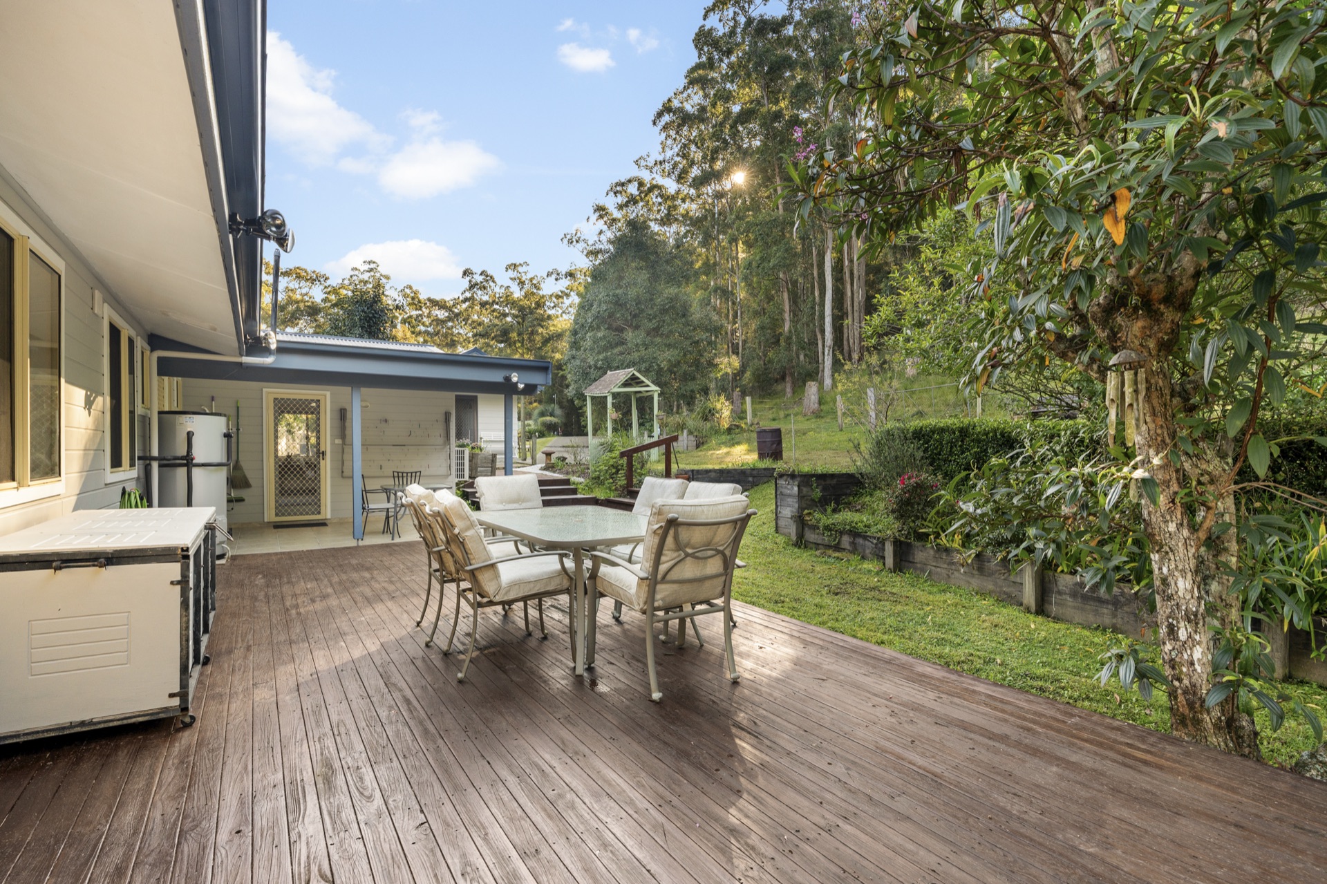 Outdoor dining deck with sloped lawn and forest backdrop